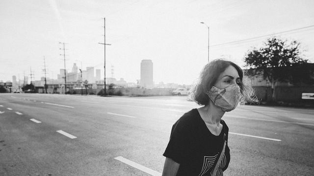 Still from the short film "Last Light" (2020) by Carmen Argote, showing a woman in a protective face mask walking down a Los Angeles road