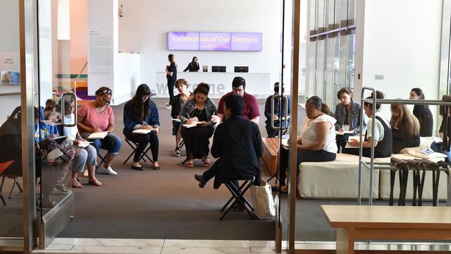 Several teachers sit on folding chairs in the Hammer lobby.