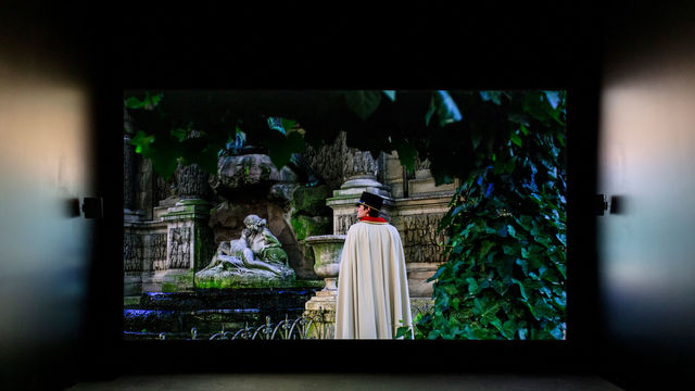 A screening room with an image of a caped man standing in a garden