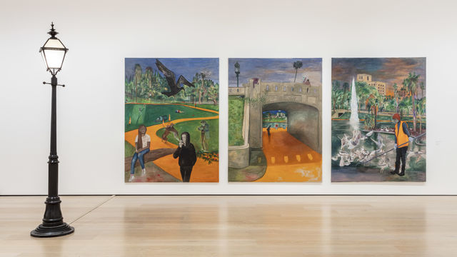 A gallery with a black streetlamp to the left of a triptych of paintings displaying MacArthur Park in Los Angeles