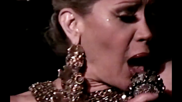 A woman in sparkly jewelry sings into a microphone