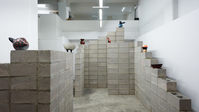 Cinder blocks arranged architecturally to hold small colorful ceramic artworks