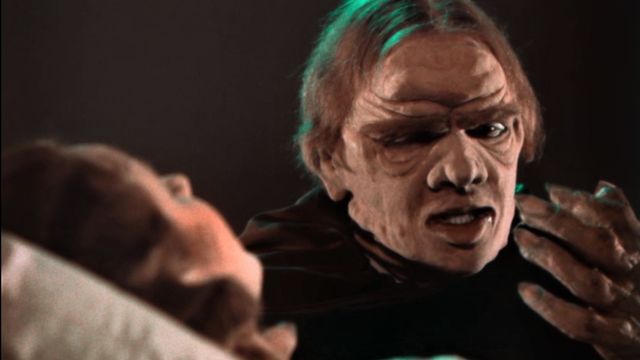 Man with wrinkles on his face speaks to a woman who is lying down.