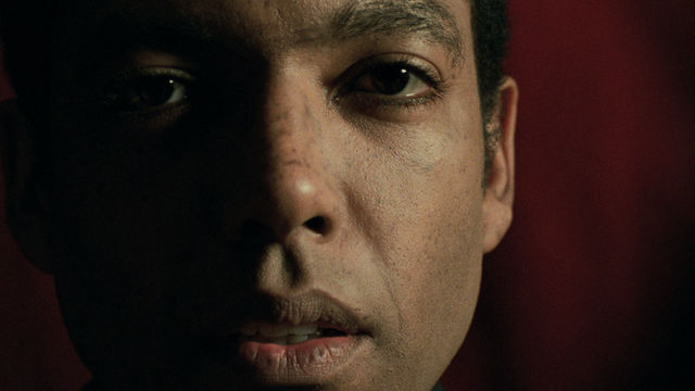 Closeup of man's face in dim lighting. Half of his face is in the shadows.