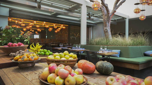 A wooden table full of fall produce and a colorful restaurant in the background.