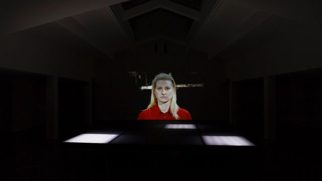 Portrait of person projected large on one wall in a big room