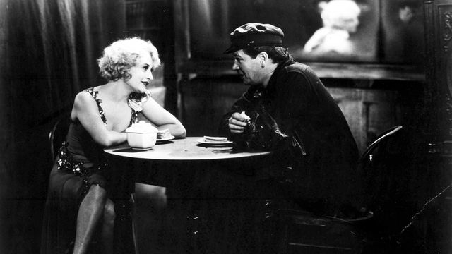 Still from the black and white film "The Docks of New York" (1928) showing a man and a woman talking at a table