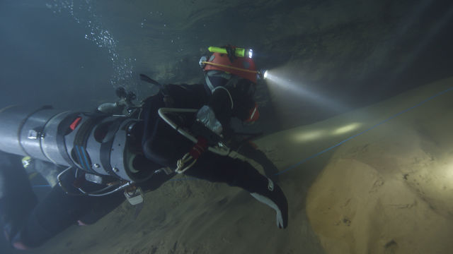 A person scuba dives close to the sand