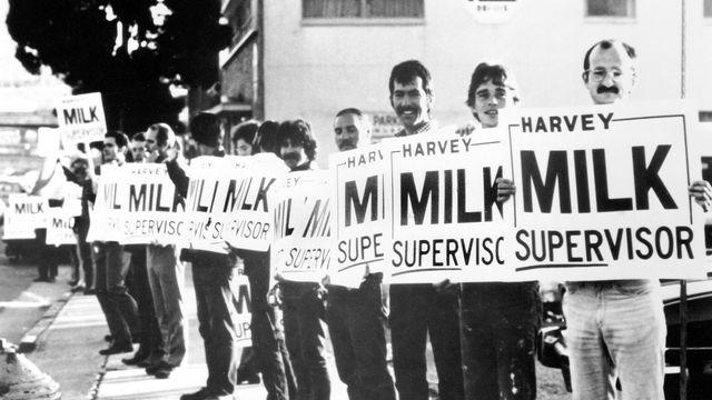 Still from the film "The Times of Harvey Milk" (1984), showing a group of men holding political campaign signs that say "Harvey Milk Supervisor"