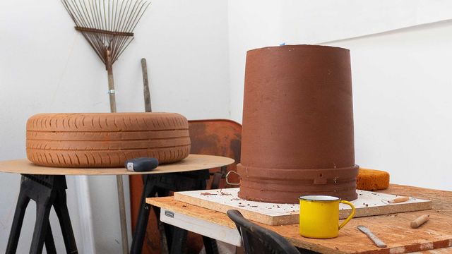 Photo of noé olivas's artist studio, showing sculptures of a tire and an upside down bucket on a worktable