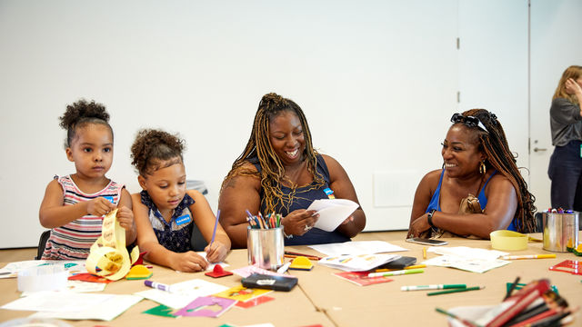 Two women and two children do arts and crafts together.