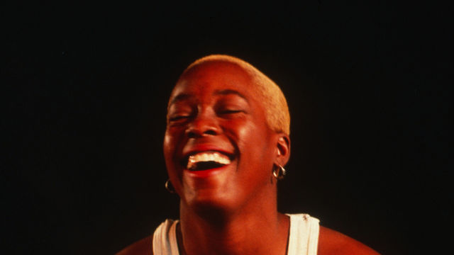 woman in a tank top with short hair laughs