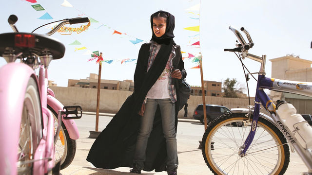 Girl stands next to two bikes. 