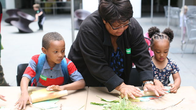 Hammer employee working with two kids to make art with leaves.