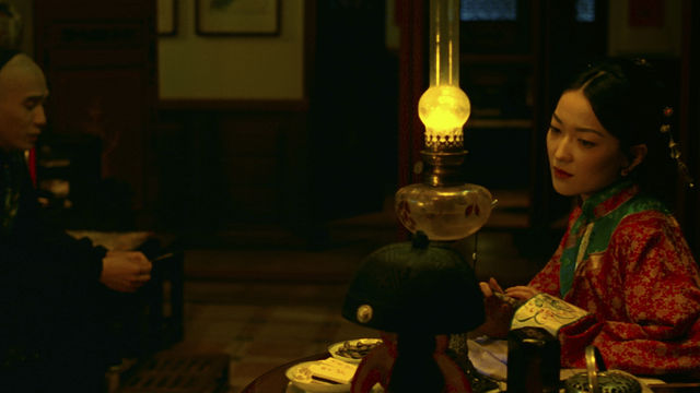A man and a woman sit in a dimly lit room.