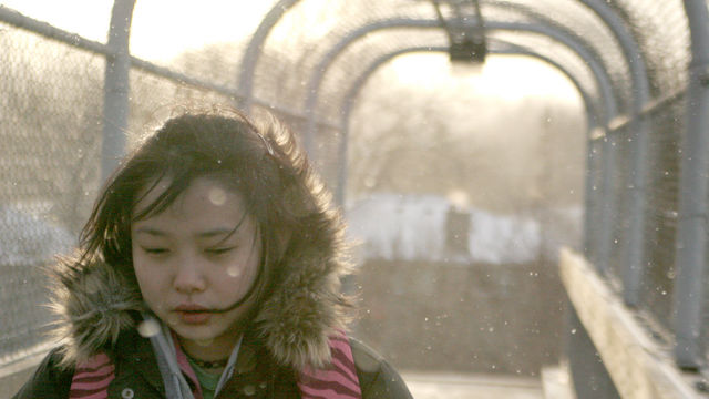 Woman in a puffy jacket walks through an archway.
