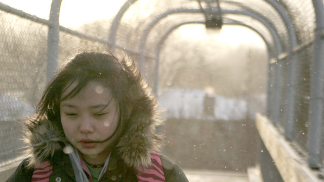 Woman in a puffy jacket walks through an archway. 