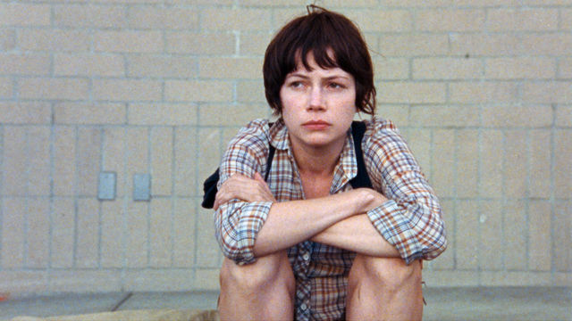 A woman sits on a sidewalk.