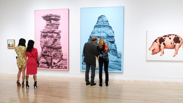 Small groups of visitors looking at paintings in a gallery