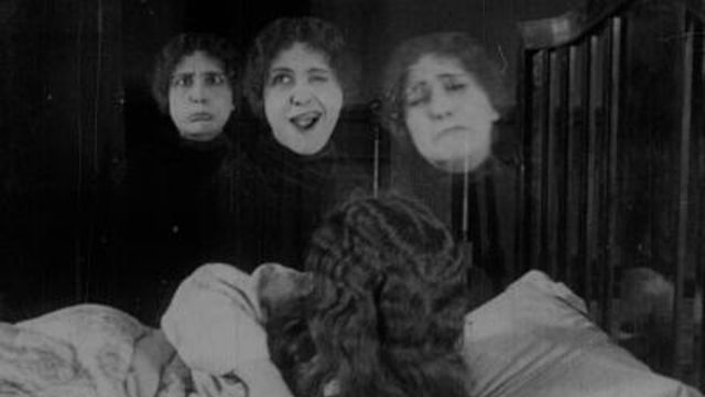 3 Triplets make different expressions next to each other in black and white photo.