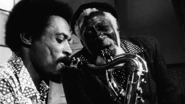 Two men play the saxaphone