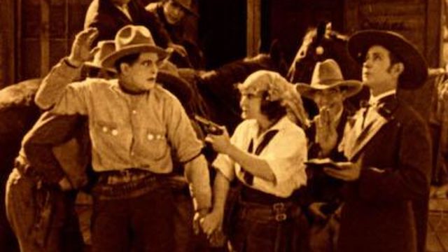 Western scene. Woman holds man in cowboy hat at gunpoint in sepia tone photo.
