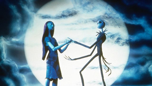 Skeletons hold hands as silohouette's in front of a setting moon