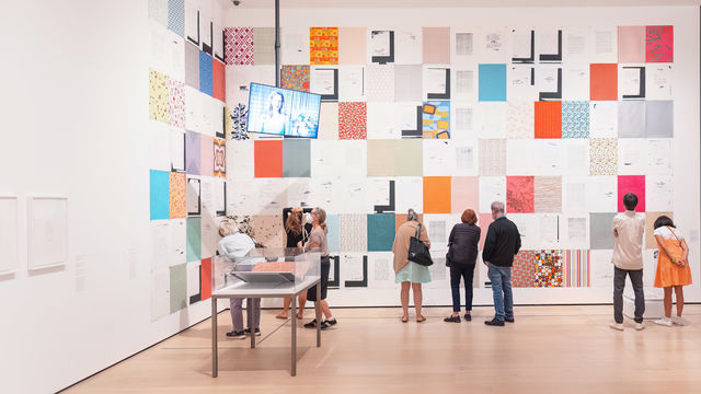 A small group of people looking at a colorful installation on a gallery wall