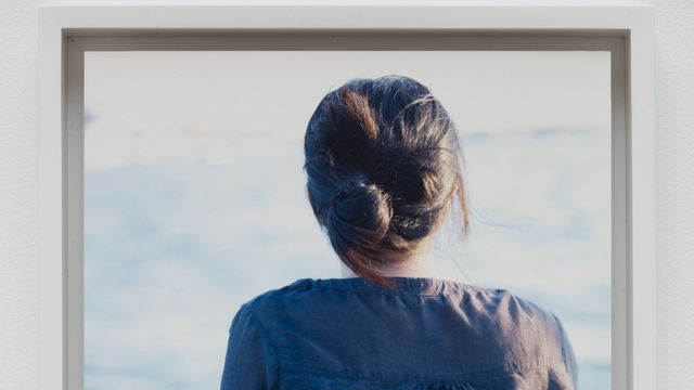 Color photo the back of a woman as she looks out over a body of water