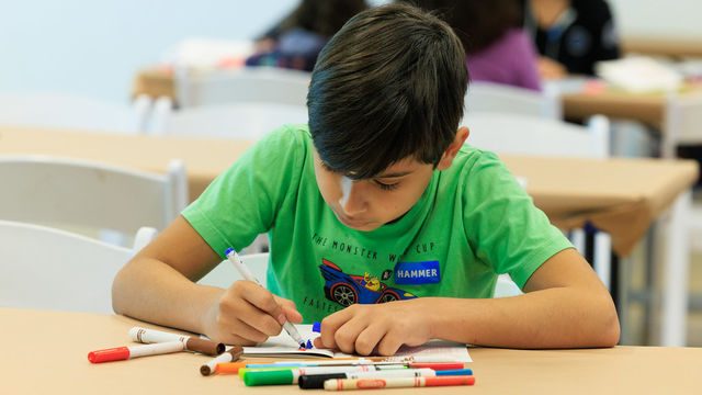 Child in a green shirt drawing with markers