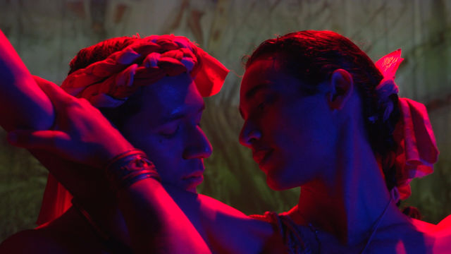 Two people look at each other intimately in blue/red light