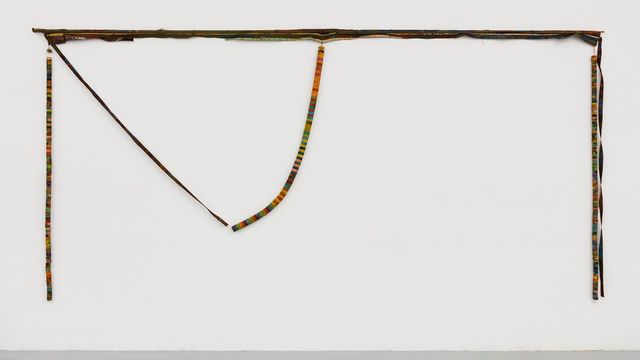 A colorful, yarn wrapped piece hanging on a wall