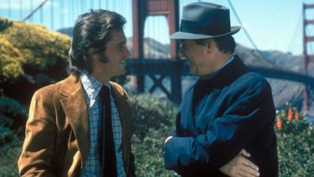 Two men talk with the Golden Gate bridge behind them
