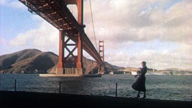 A woman stands at the waterfront in front of the Golden Gate Bridge