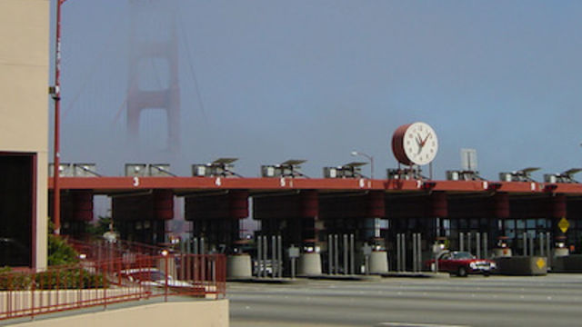 A toll booth with the Golden Gate Bridge in the distance, shrouded by fog