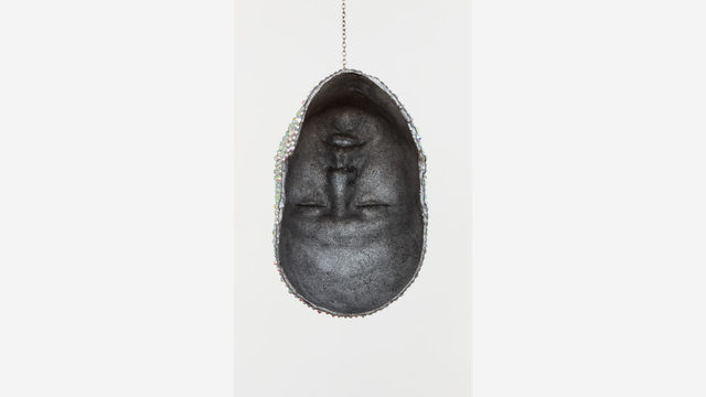 The artist's face, upside down and encircled by jewels