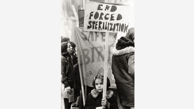 A girl holding a sign reading "End Forced Sterilization"