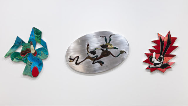Three sculptural works on a wall, each representing Wile E. Coyote