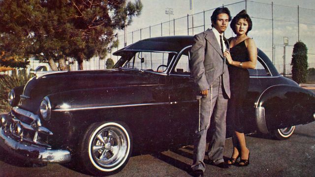 Photo of a couple standing in front of a vintage car