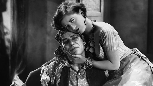 A woman cradles the dead of a man who holds a lit cigarette between his toes