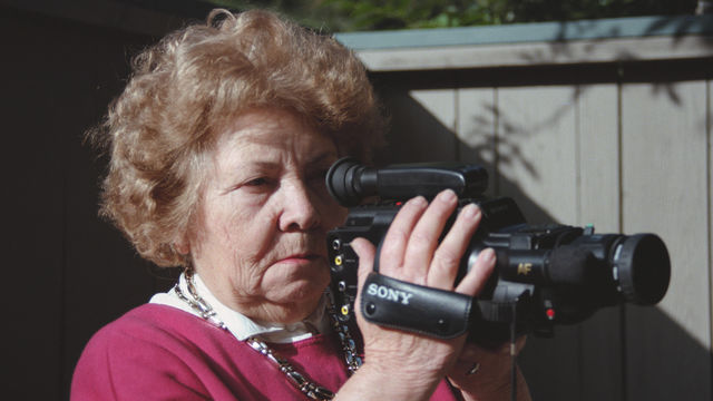 An elderly woman holds a video camcorder