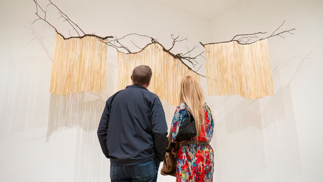 Two visitors look up at a hanging artwork