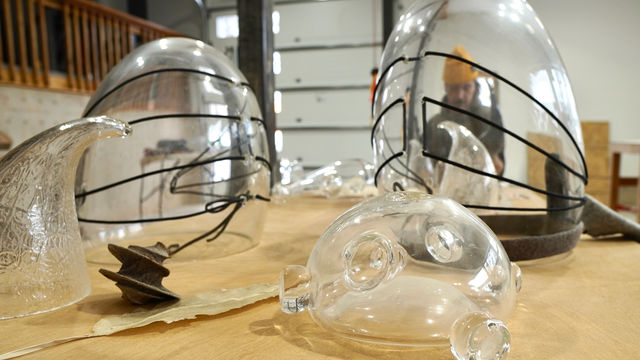 Blown glass shapes, through which is visible a distorted view of the artist