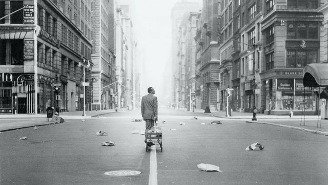 Harry Belafonte pulls a wagon behind him as he walks through a desolate city street
