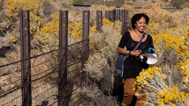 Krystle Hickman stands in a nature preserve holding a camera