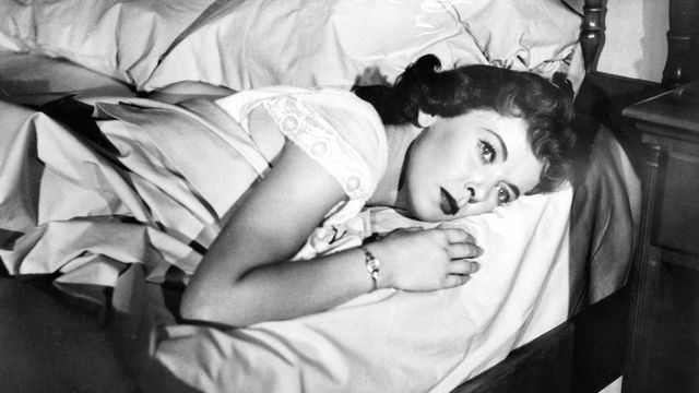 Joan Fontaine laying in a bed