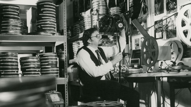 Black and white photo of Bob Rosen inspecting a reel of 35mm film