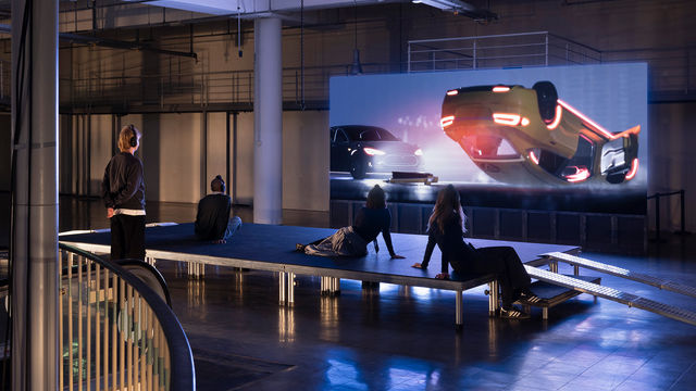 Gallery view of visitors watching a video with an overturned car