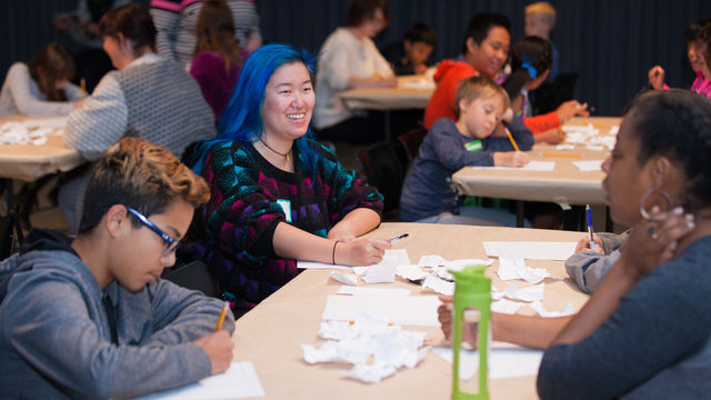 Smiling young teens sit at a table and write
