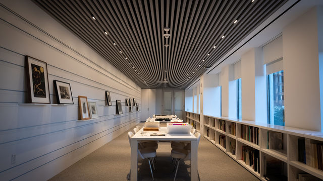 Empty room with tables and walls covered in works on paper